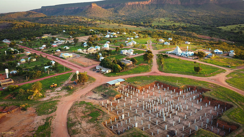 Vista aérea da comunidade Zigurats com casas em domo, serras ao fundo e obra em construção